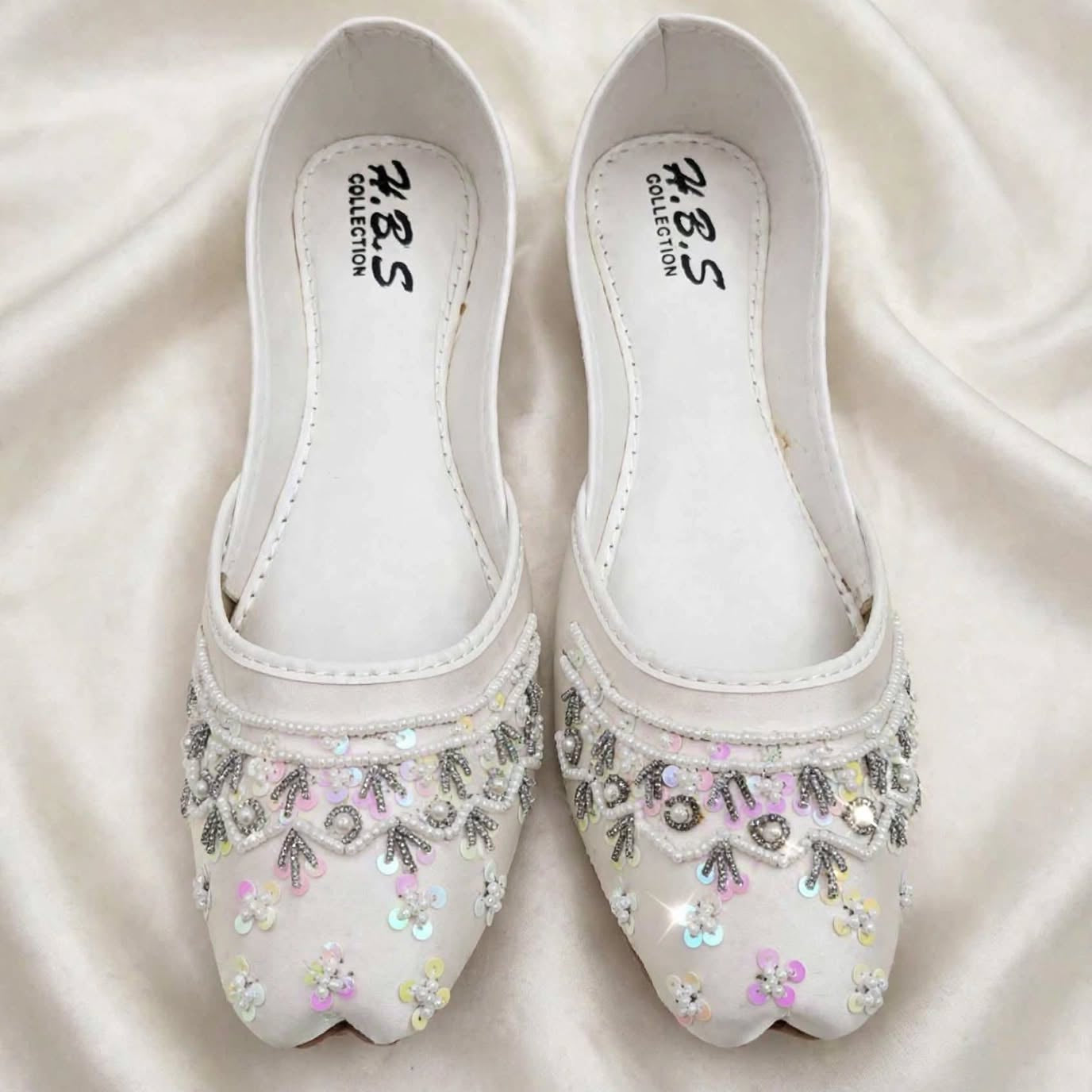 Ivory Rosette Bridal Khussa on fabric background, Her Footwear Pakistan